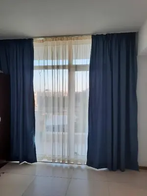 a room with a large window with blue curtains at Grand Kamelia Apartment in Sunny Beach