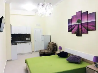 a room with a green bed and a kitchen at Stamopolu Lux ground floor in Primorsko