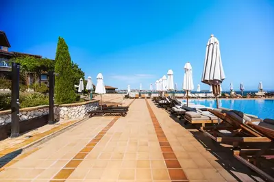 a row of chairs and umbrellas next to a pool at LUXURY APARTMENT Sozopolis in Sozopol