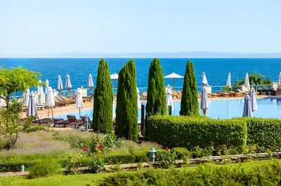 a resort with a pool and umbrellas and the ocean at LUXURY APARTMENT Sozopolis in Sozopol
