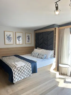 a bedroom with a king sized bed and a chair at Wavehaven Apartment at South Bay in Varna City