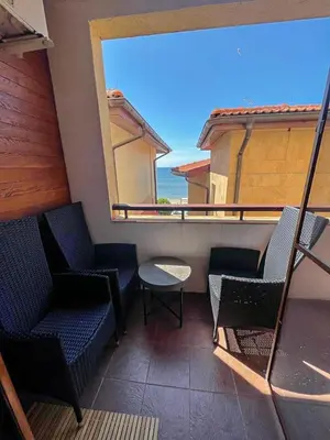 a balcony with chairs and a table and a large window at Apartmány Bulharsko Sveti Vlas - Garden of Eden in Sveti Vlas