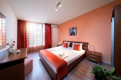 a bedroom with a large bed with orange walls at Aurelia Beach Complex in Ravda