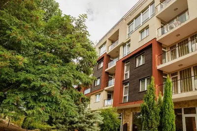 an apartment building with trees in front of it at Dune Residence Apartments in Sunny Beach