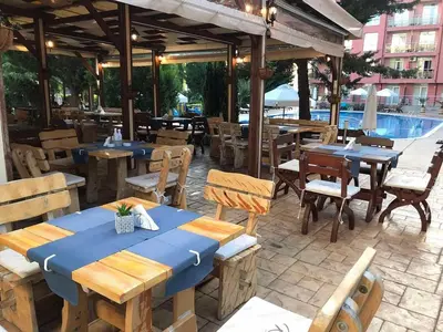 a restaurant with tables and chairs and a pool at Rainbow Luci in Sunny Beach