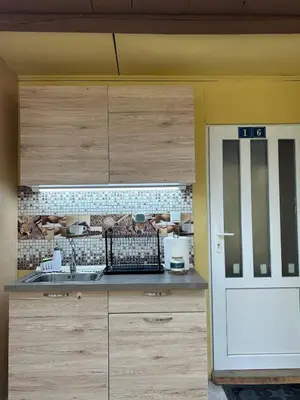 a kitchen with wooden cabinets and a white door at Бунгала Мишел in Varna City