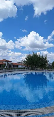 a large swimming pool with a blue sky with clouds at Studio M in Sveti Vlas