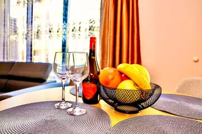 a table with two wine glasses and a bowl of fruit at Sea Sun Holiday Apartments Sunny Beach in Sunny Beach