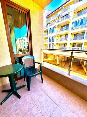 a balcony with a table and a chair and a window at Sea Sun Holiday Apartments Sunny Beach in Sunny Beach