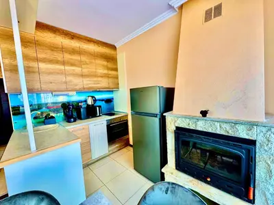 a kitchen with a fireplace and a refrigerator at Sea Sun Holiday Apartments Sunny Beach in Sunny Beach