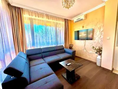 a living room with a blue couch and a table at Sea Sun Holiday Apartments Sunny Beach in Sunny Beach