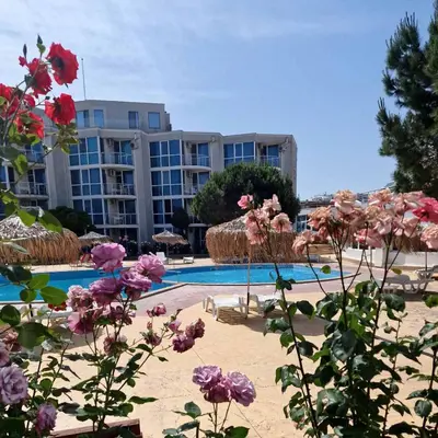 a pool with pink flowers in front of a building at Апартамент БАНГЕВИ in Burgas City