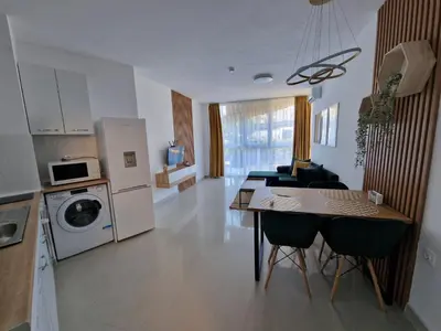 a kitchen and living room with a table and chairs at Апартамент БАНГЕВИ in Burgas City
