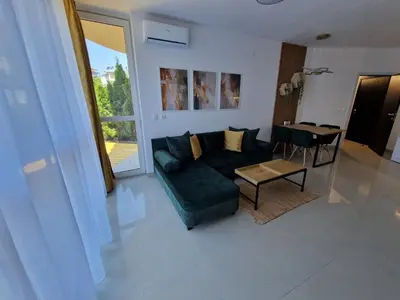 a living room with a green couch and a table at Апартамент БАНГЕВИ in Burgas City