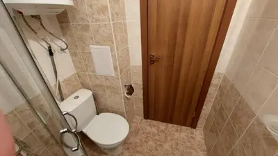 a bathroom with a toilet and a wooden door at Sunny Day 6 , Sunny beach, 3-Стаен апартамент in Tŭnkovo