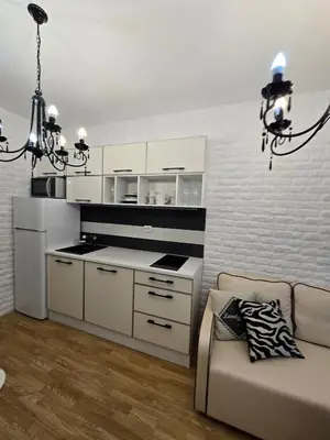 a kitchen with white cabinets and a couch and a chandelier at A wonderful vacation home in Sunny Beach