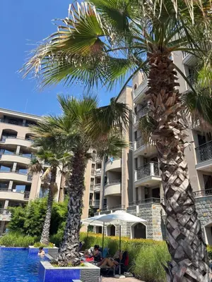 a hotel with palm trees in front of a swimming pool at Cascadas Family Studio Komfort dla Dwojga lub Rodziny in Sunny Beach