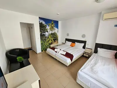 a hotel room with two beds and a chair at Mirage Family Hotel in Primorsko