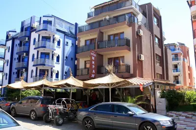 a building with umbrellas and cars parked in front of it at Mirage Family Hotel in Primorsko