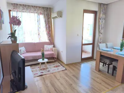 a living room with a pink couch and a tv at Apartment Rilska - Center and Sea Garden in Burgas City