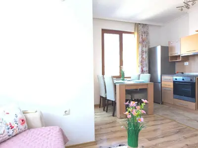 a living room and kitchen with a table and a vase of flowers at Apartment Rilska - Center and Sea Garden in Burgas City