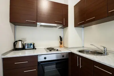 a small kitchen with wooden cabinets and a sink at Seaside 1 BR Apartment with balcony, max 4 Guests in Sunny Beach