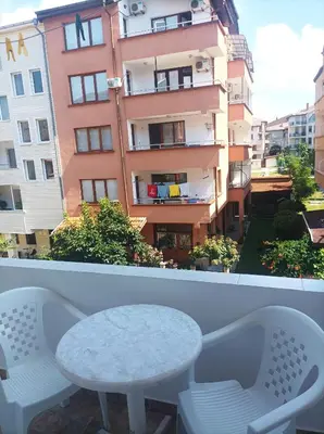 a white table and chairs on a balcony with a building at Family Hotel Magnolia - Summer residence in Primorsko