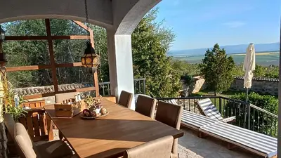 a wooden table and chairs on a balcony with a view at къщи за гости villa Momino in Avren