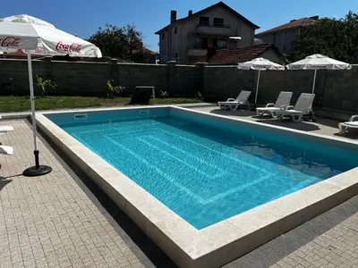 a swimming pool with two chairs and an umbrella at Obzor in Obzor