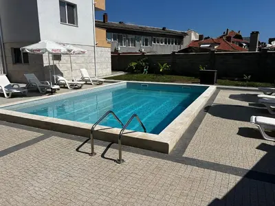 a swimming pool with chairs and an umbrella at Obzor in Obzor
