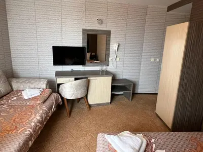a hotel room with a desk and a couch and a television at Hotel Lazur in Kiten