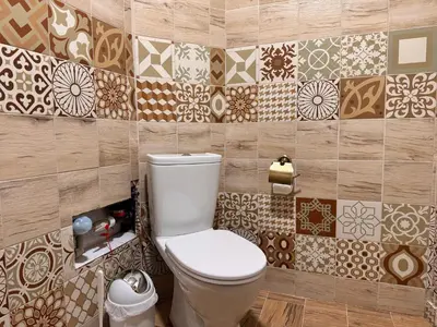 a bathroom with a toilet and tiles on the wall at Cozy Central Apartment Steps from Everything! in Varna City