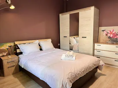a bedroom with a large bed and a dresser at Cozy Central Apartment Steps from Everything! in Varna City