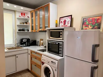 a kitchen with a refrigerator and a washer and dryer at Cozy Central Apartment Steps from Everything! in Varna City