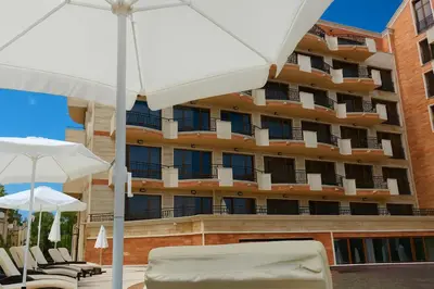 a hotel with chairs and umbrellas in front of a building at River Park Menada Apartments in Sunny Beach