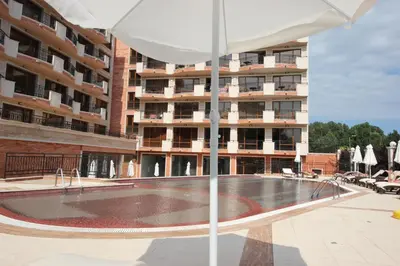 an empty pool with an umbrella in front of a building at River Park Menada Apartments in Sunny Beach