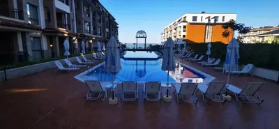 a pool with chairs and umbrellas on a patio at Ах, морето 2 in Burgas City