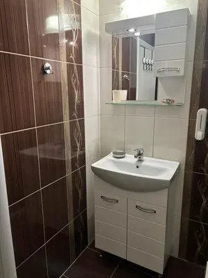 a bathroom with a sink and a shower with a mirror at Apartment 4 Plus Burgas in Burgas City