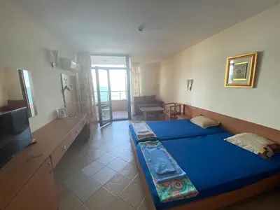 a bedroom with a blue bed and a living room at Sozopol Sunrise in Sozopol