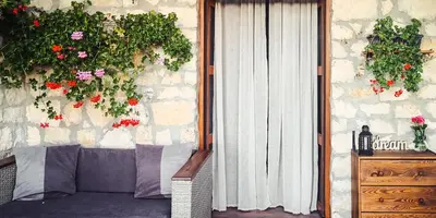 a patio with a couch and flowers on a wall at къща за гости villa Jurta in Avren