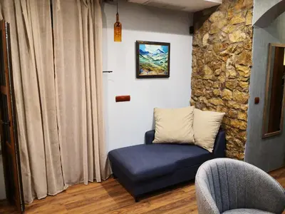 a living room with a blue couch and a stone wall at къща за гости villa Jurta in Avren