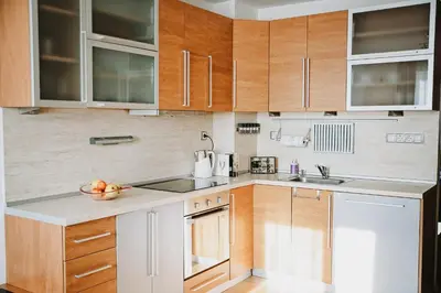 a kitchen with wooden cabinets and a bowl of fruit on the counter at Smile City Apartment in Varna City