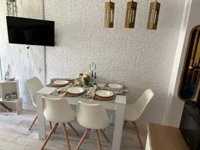 a white dining room table with white chairs and a tv at Студио в Затворен Комплекс Green in Sozopol