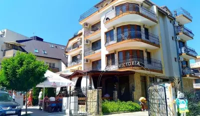 a large building with people sitting outside of it at Vila Victoria Primorsko in Primorsko