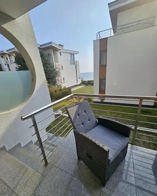 a wicker chair sitting on the balcony of a house at Двустаен апартамент Поморие in Pomorie