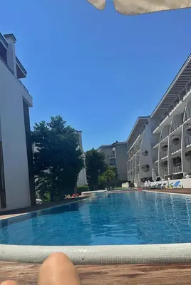 a person laying on a bench next to a swimming pool at Двустаен апартамент Поморие in Pomorie