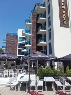 a hotel with tables and umbrellas in front of a building at SUN GATE - Julia in Sunny Beach