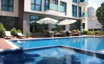 a swimming pool in front of a building with umbrellas at SUN GATE - Kamil in Sunny Beach