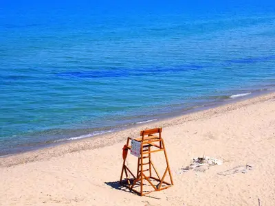 a chair sitting on a beach next to the ocean at Апартамент Деа - Apartment Dea in Byala