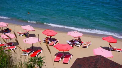a group of pink umbrellas and chairs on the beach at Апартамент Деа - Apartment Dea in Byala